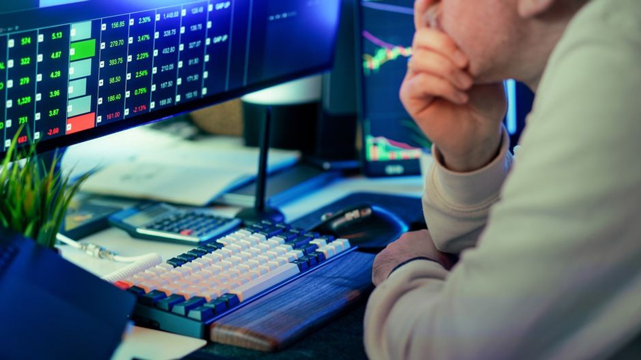 Professional car shipping broker researching carriers on computer with multiple screens