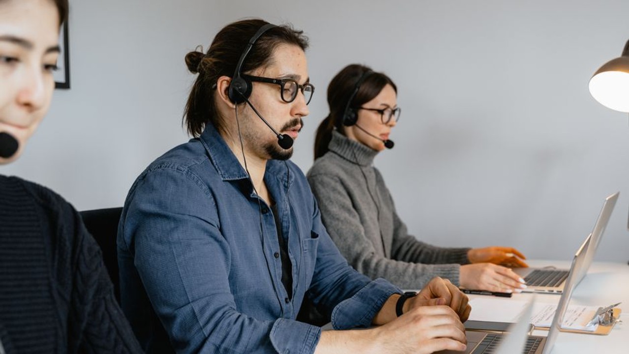 Customer service representative on the phone, explaining car shipping delay updates to a client, emphasizing transparent communication