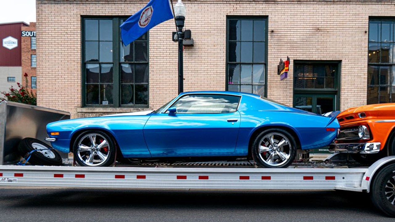 Classic red sports car being carefully winched onto an enclosed auto transport trailer for secure and protected shipping