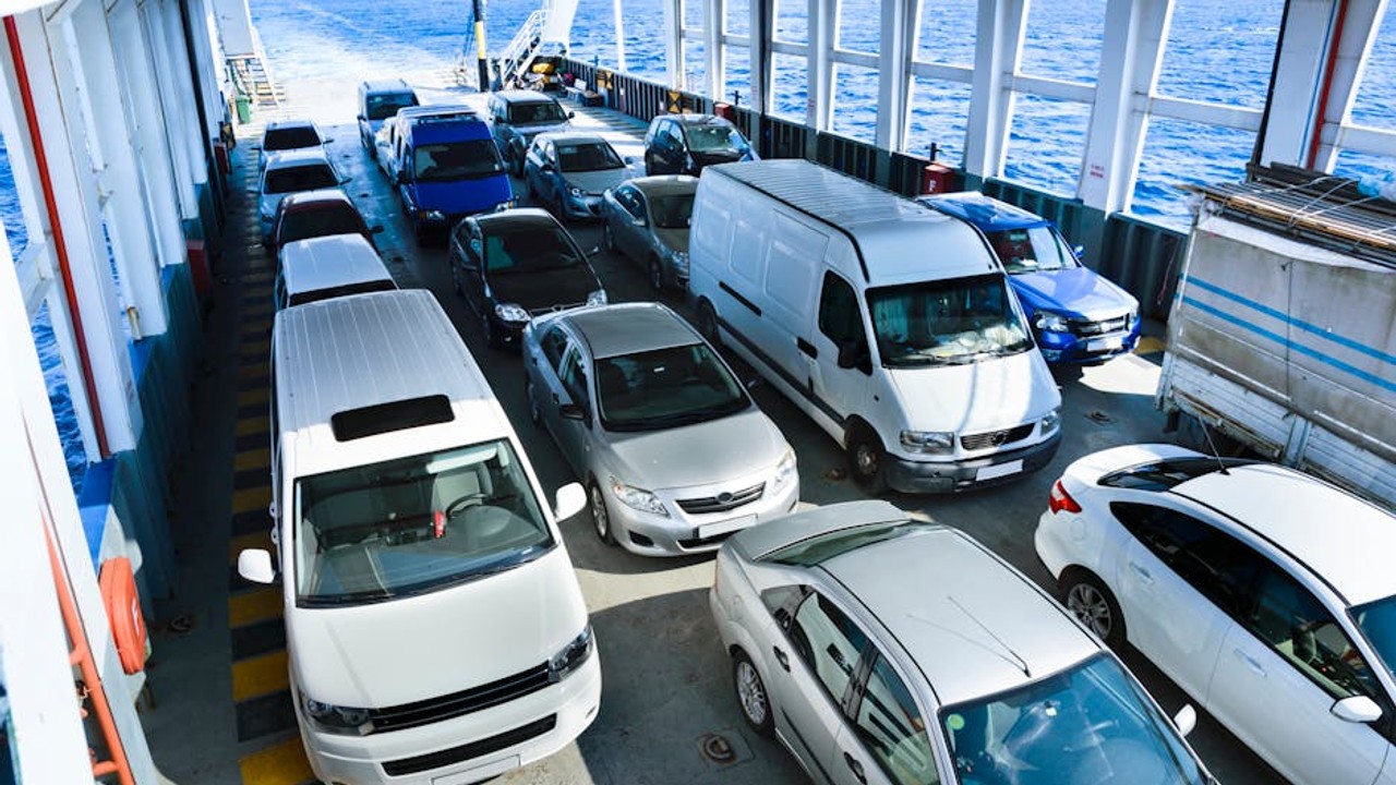Happy couple waving goodbye to a car carrier truck as their car is being loaded, symbolizing a stress-free car shipping experience.