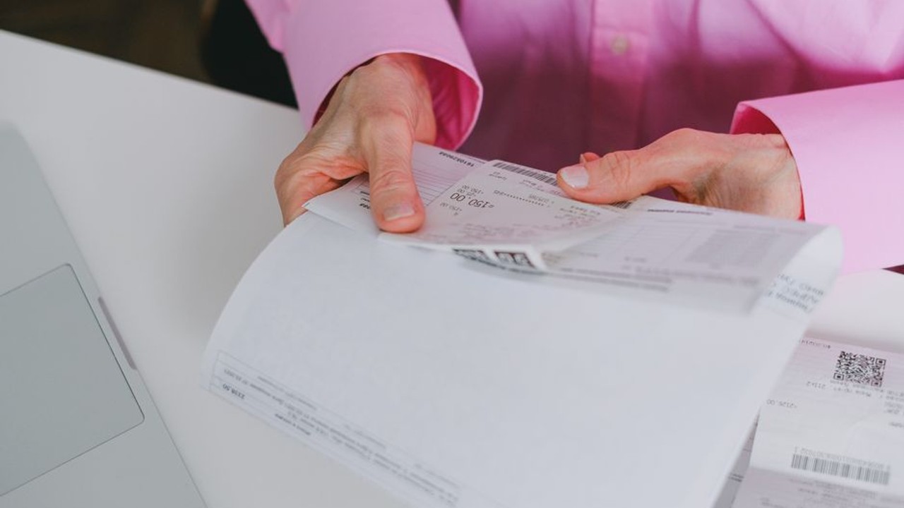 Close-up of a hand highlighting numbers on a car shipping invoice, emphasizing the importance of detailed record-keeping for tax purposes