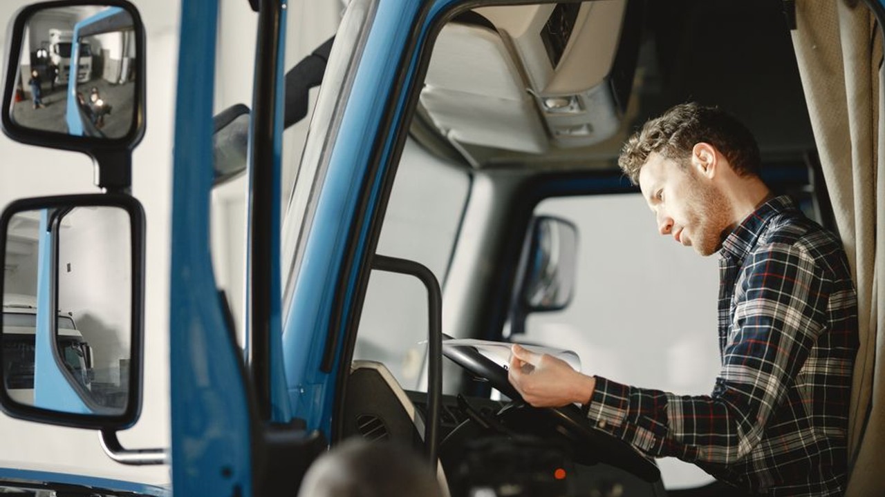 Car interior being checked for personal belongings before cross-country shipping, with a checklist on the dashboard.