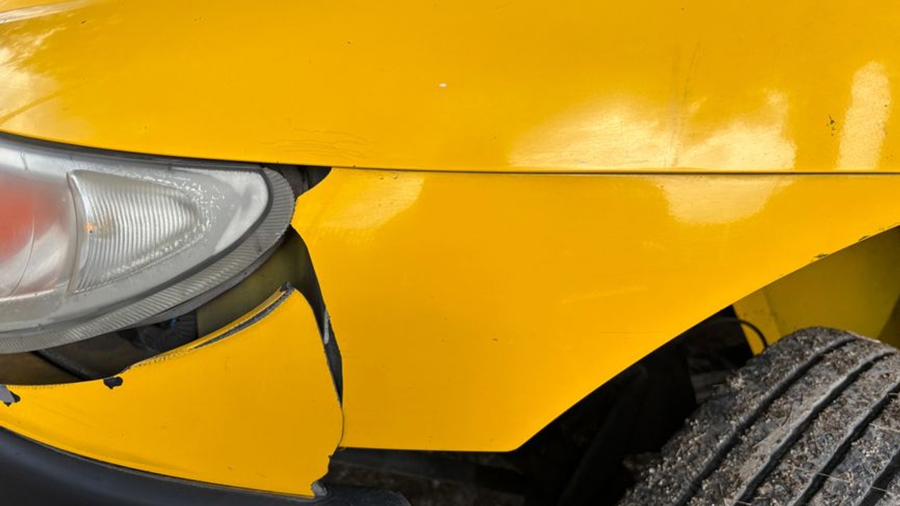 Detailed close-up inspection of a car's exterior, highlighting pre-shipping damage documentation with a smartphone camera, stressing insurance importance