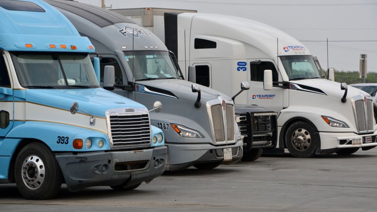 exhaust fumes coming from a semi-truck carrying cars on a busy highway