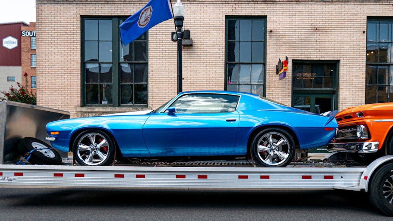 Professional car hauler loading a vintage car onto an enclosed auto transport trailer, emphasizing careful handling