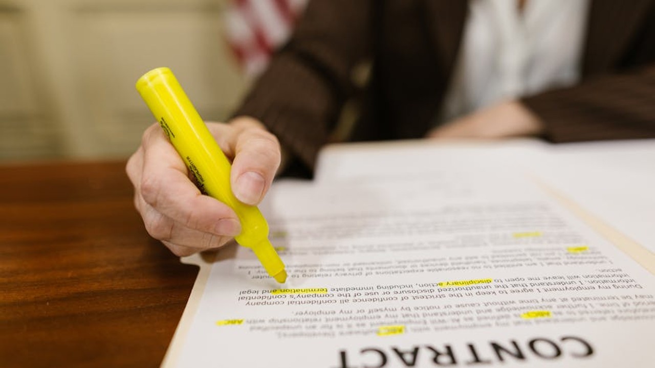 Woman speaking on phone next to a detailed car shipping agreement, highlighting the importance of clear communication and reading fine print