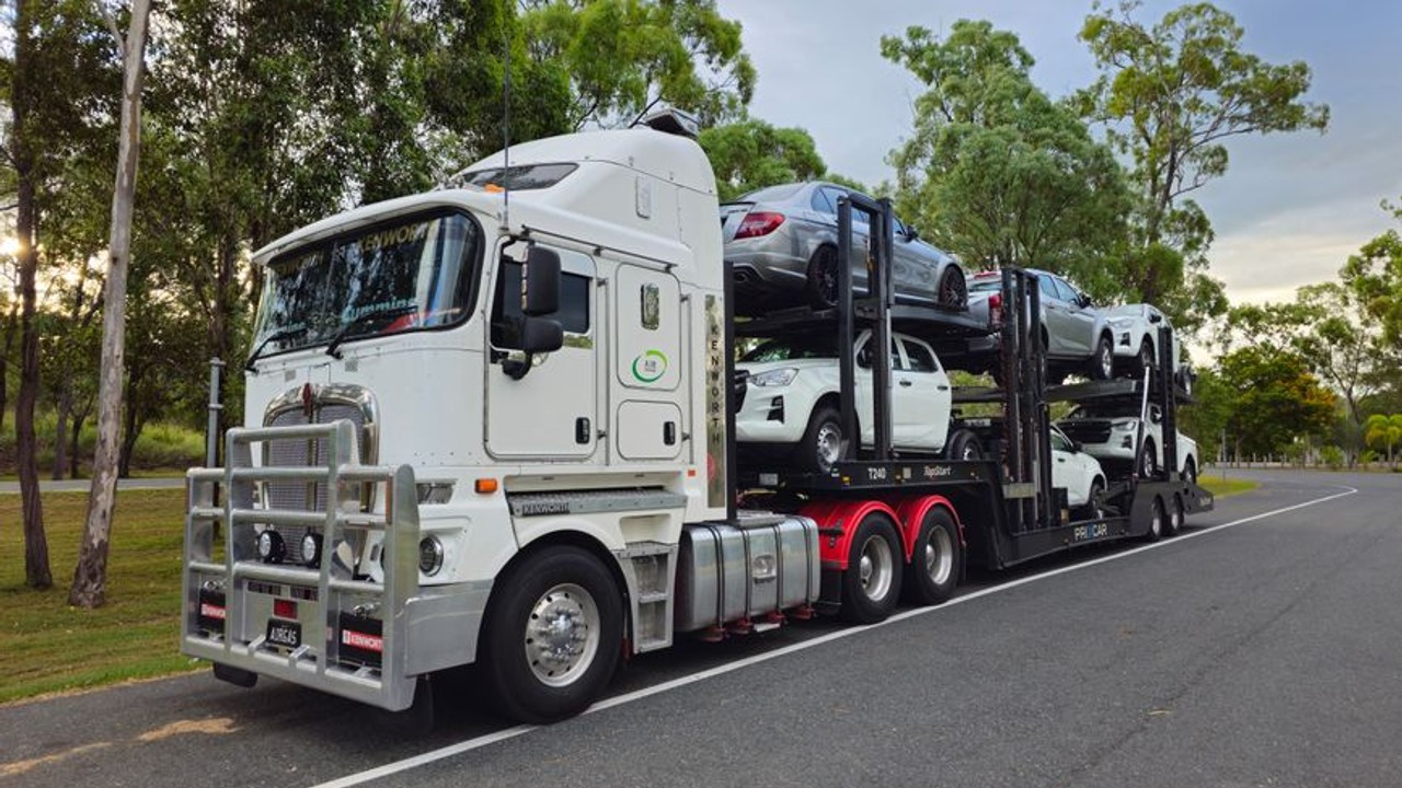 Modern car carrier loading a luxury sedan onto an enclosed auto transport trailer for secure cross country shipping