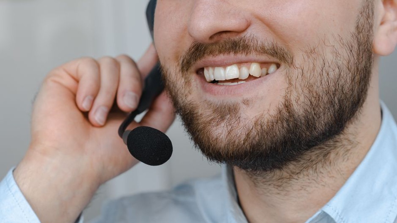 Professional customer service representative for an auto transport company smiling while speaking on a headset, demonstrating friendly and helpful assistance for car shipping inquiries.