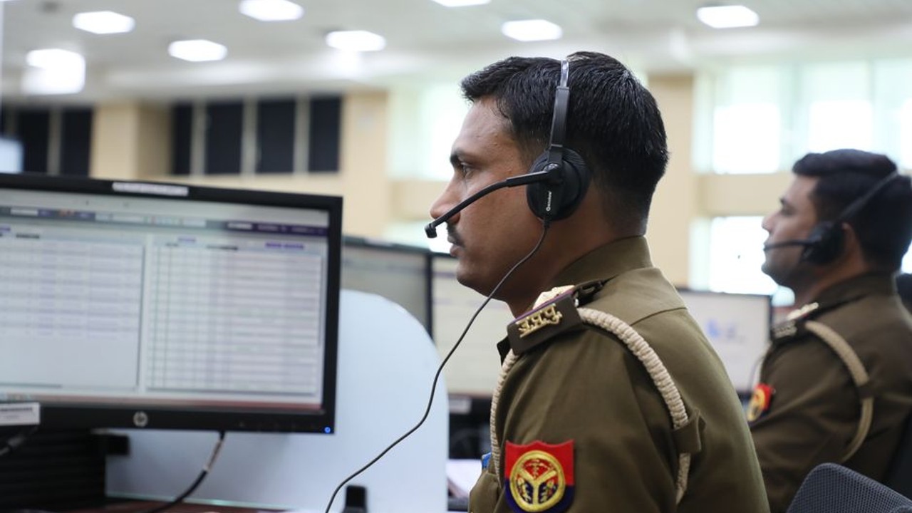 Professional auto transport dispatcher communicating on headset, surrounded by monitors displaying shipping routes and logistics data
